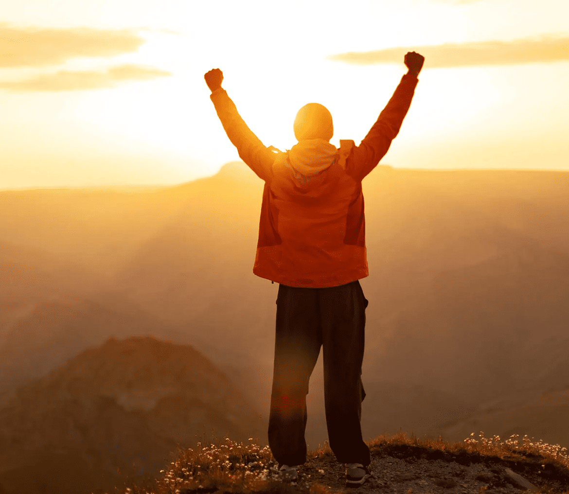 Person celebrating sunrise on mountain top